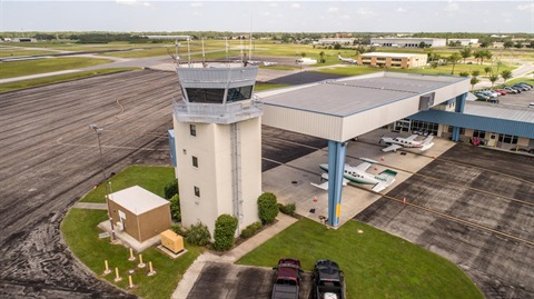 a picture showing an airport tower with landed planes at dusk